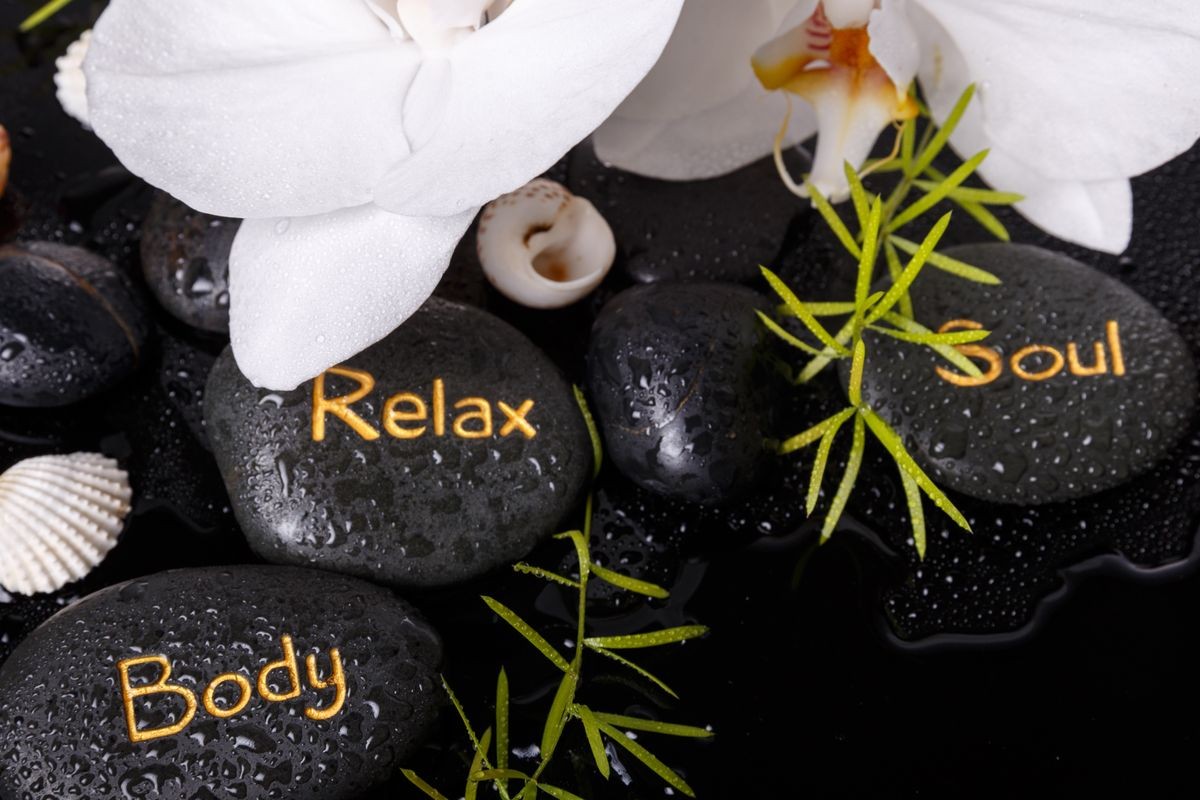 Spa concept with white orchids and black therapy stones with the inscription soul, body, and relax on black background