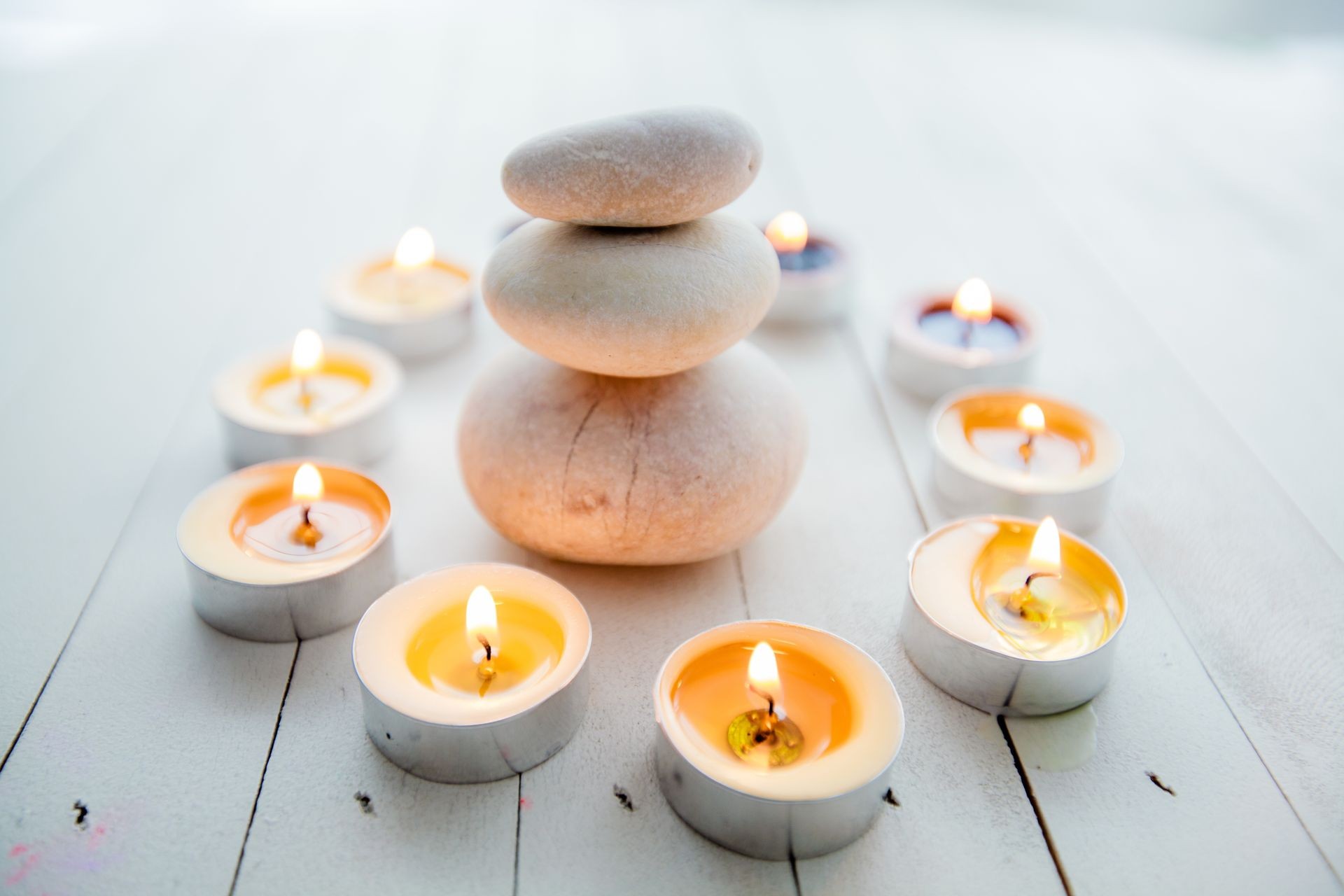 Zen Meditation Harmony, Spa Lifestyle, balanced stack of stones with aromatic candles on wooden white background